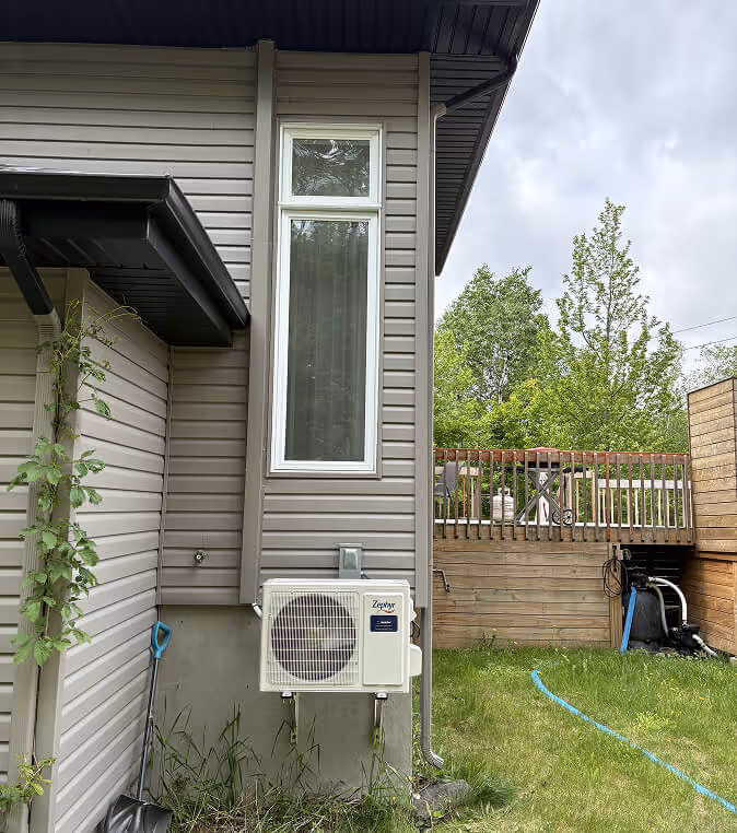 Maison moderne avec pompe à chaleur, baie vitrée, balcon en bois et jardin.