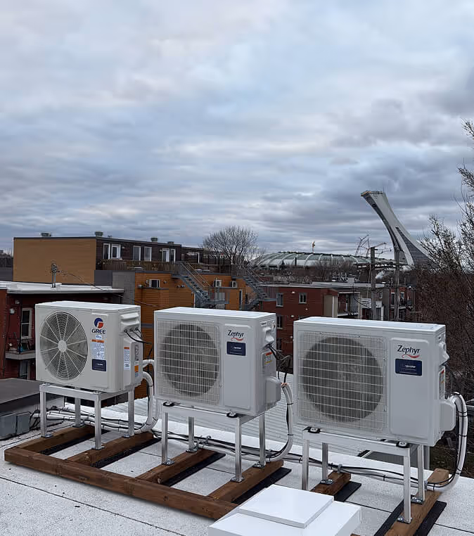 Trois unités de climatisation extérieures blanches sur un toit urbain.