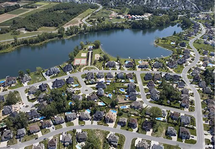 Vue aérienne d'un quartier résidentiel avec lac et maisons luxueuses entourées de verdure