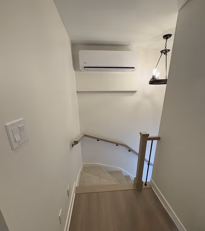 Escalier moderne avec climatisation, étagère murale et luminaire suspendu.