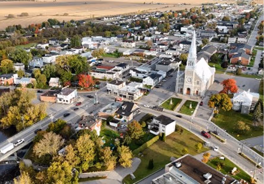 Vue aérienne d'une petite ville avec église blanche, routes, maisons et arbres d'automne.