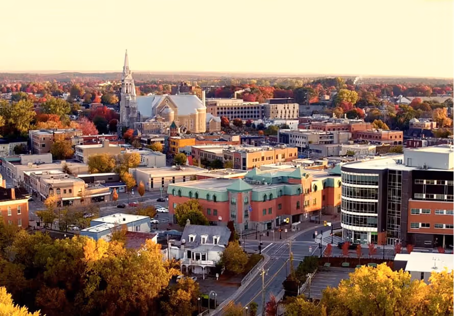 Vue aérienne d'une ville avec église, bâtiments colorés et arbres d'automne.