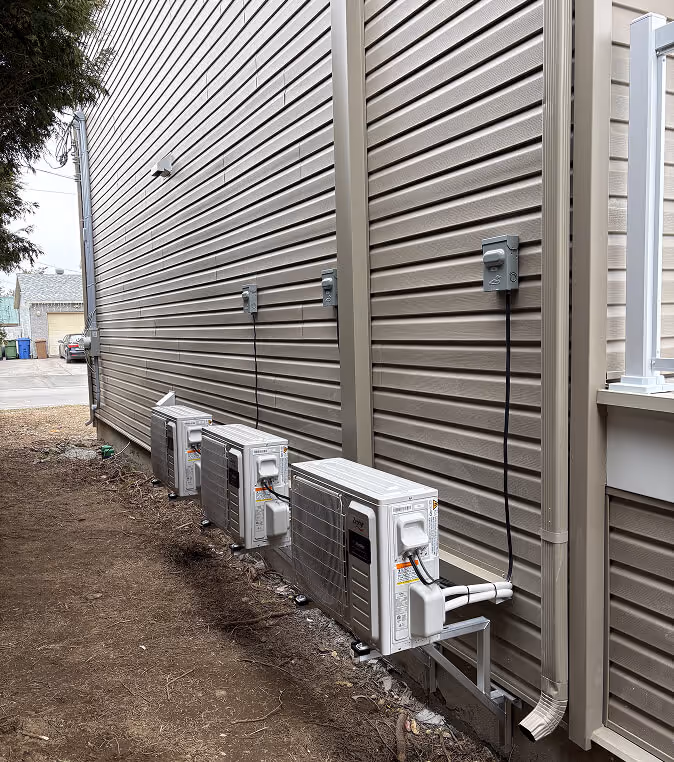 Unités de climatisation extérieures installées contre mur métallique strié gris