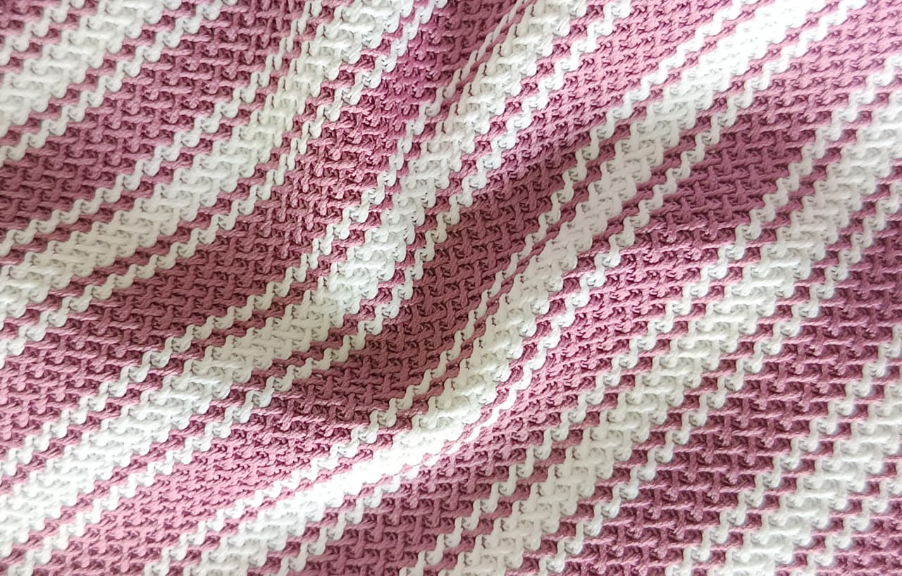 Close-up of soft, wrinkled pink cotton fabric displaying fine weave texture.