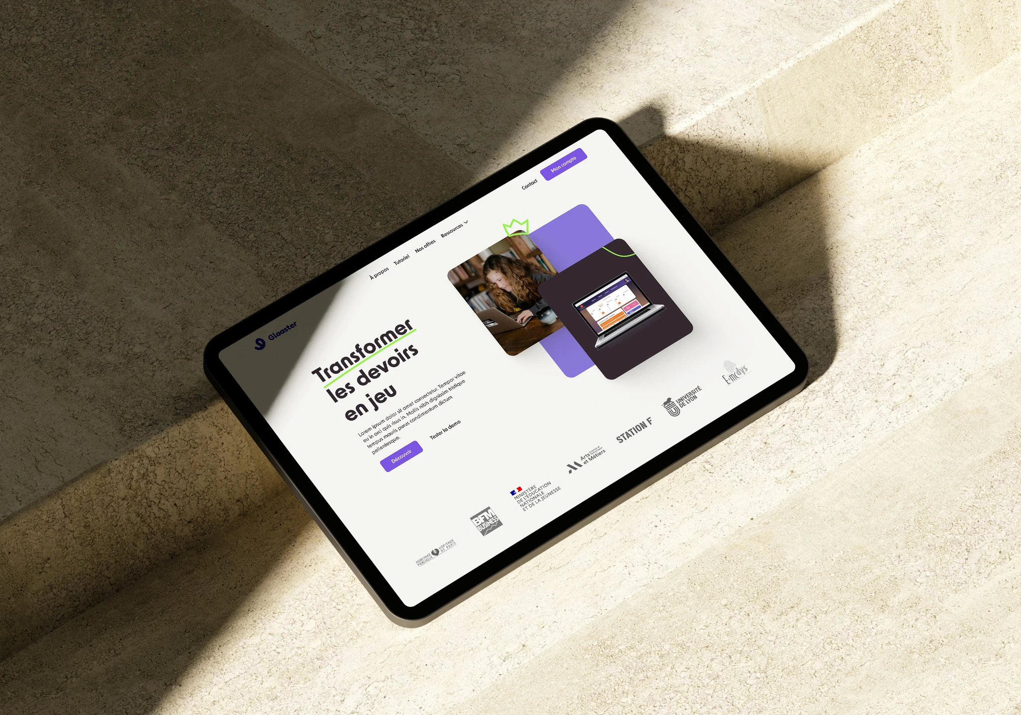 Tablet displaying a French educational website homepage with the headline 'Transformer les devoirs en jeu' and images of a woman using a laptop and a laptop screen showing a dashboard.