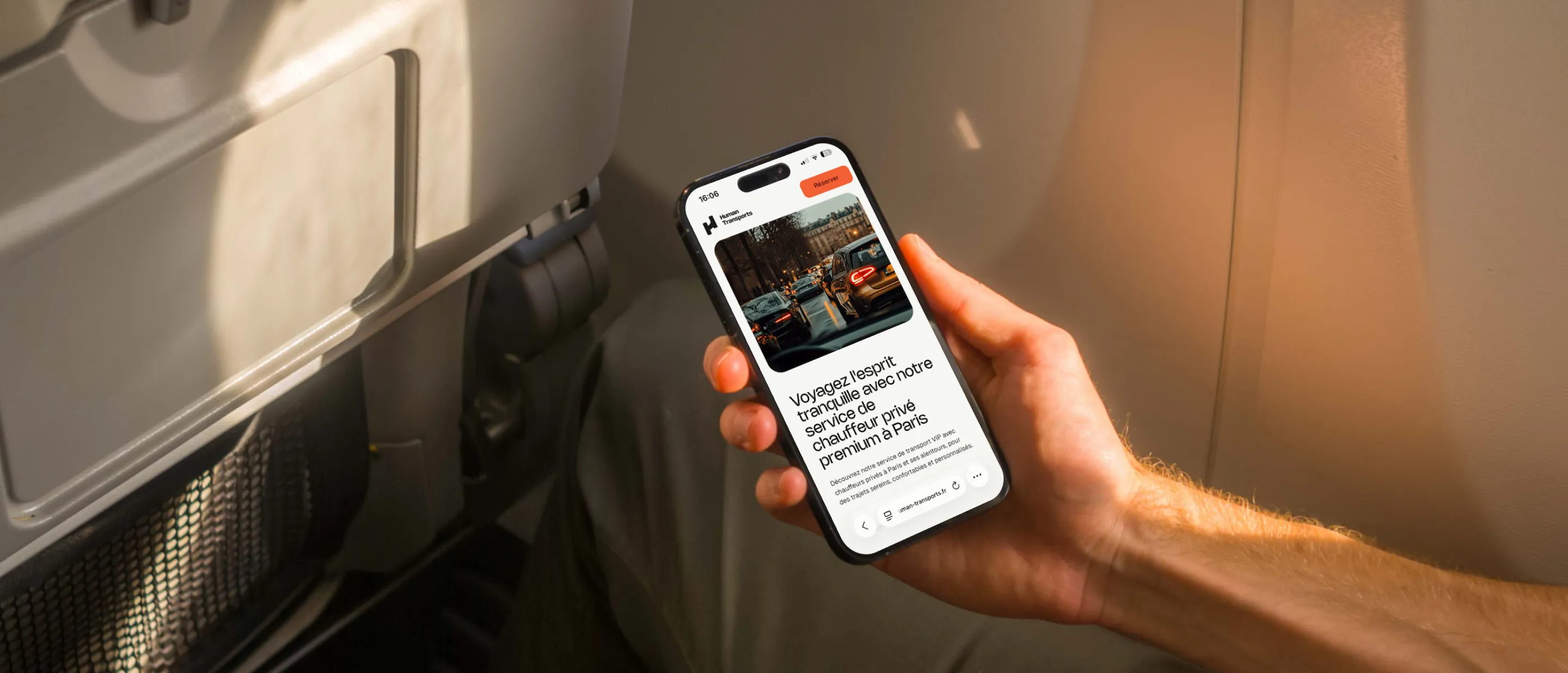 Person holding a smartphone displaying a French app for premium private chauffeur service in Paris, seated inside an airplane.