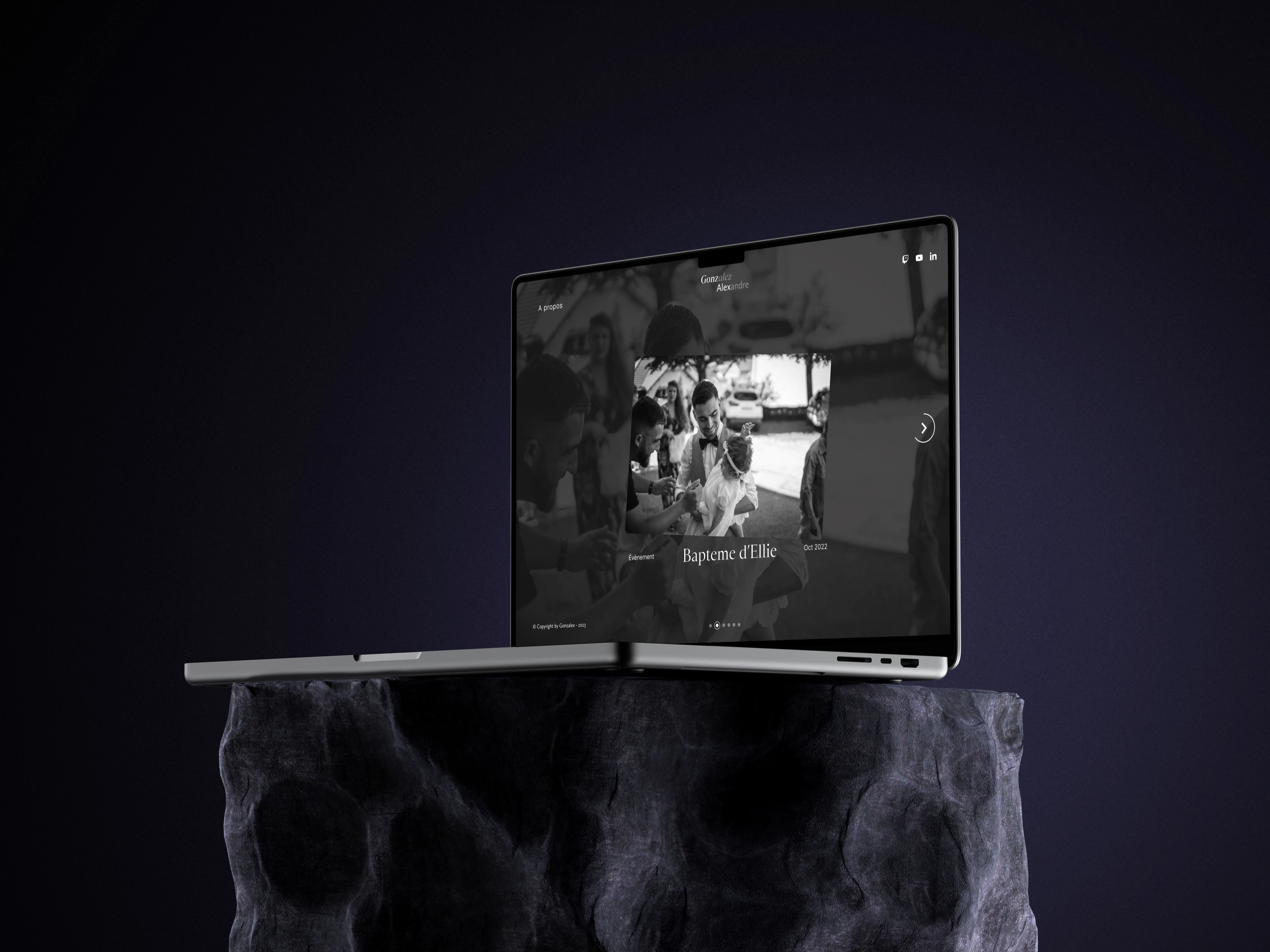MacBook Pro laptop with a black and white photo slideshow on screen, placed on a textured stone pedestal against a dark gradient background.