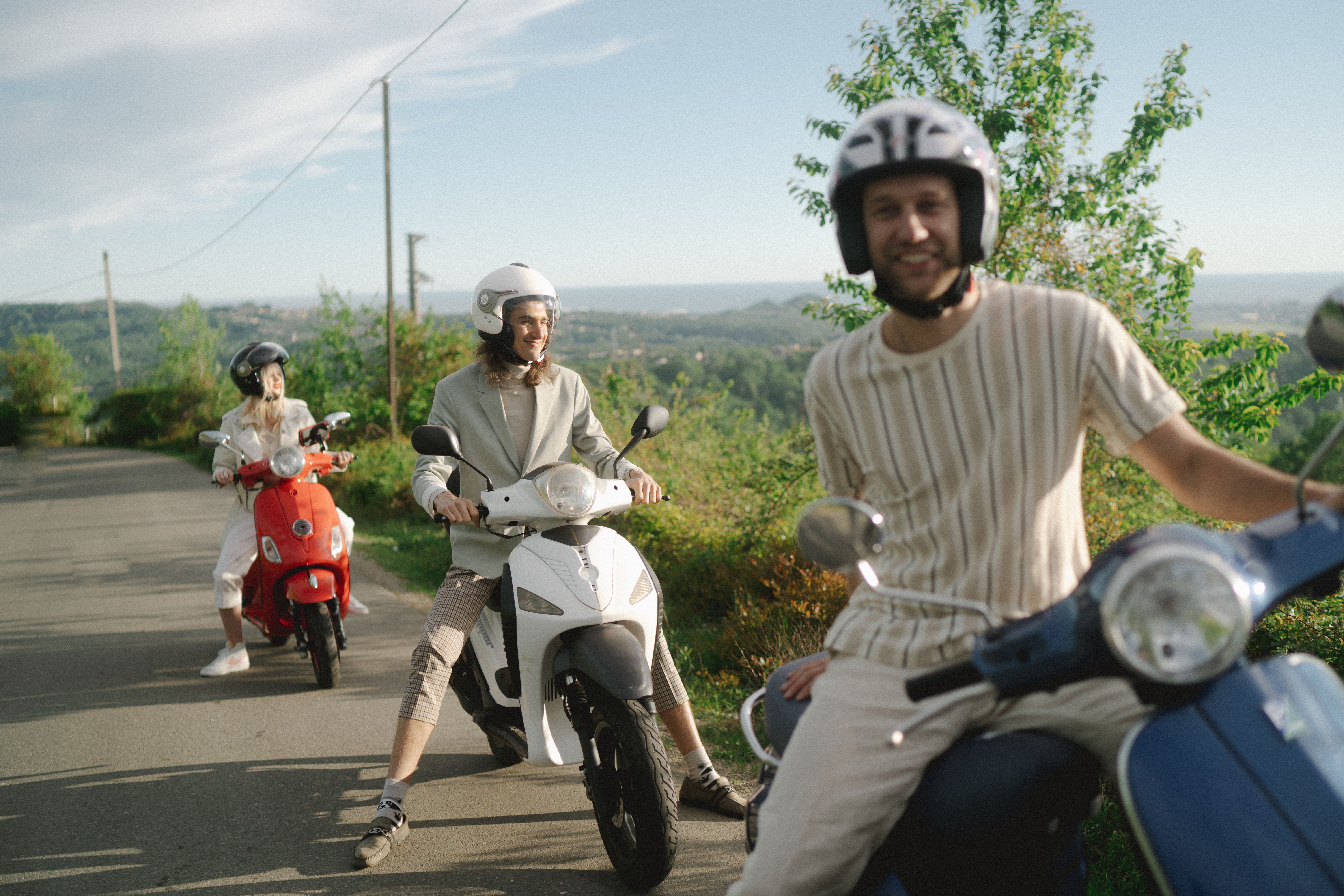 Friends riding scooters together along a tropical forest road