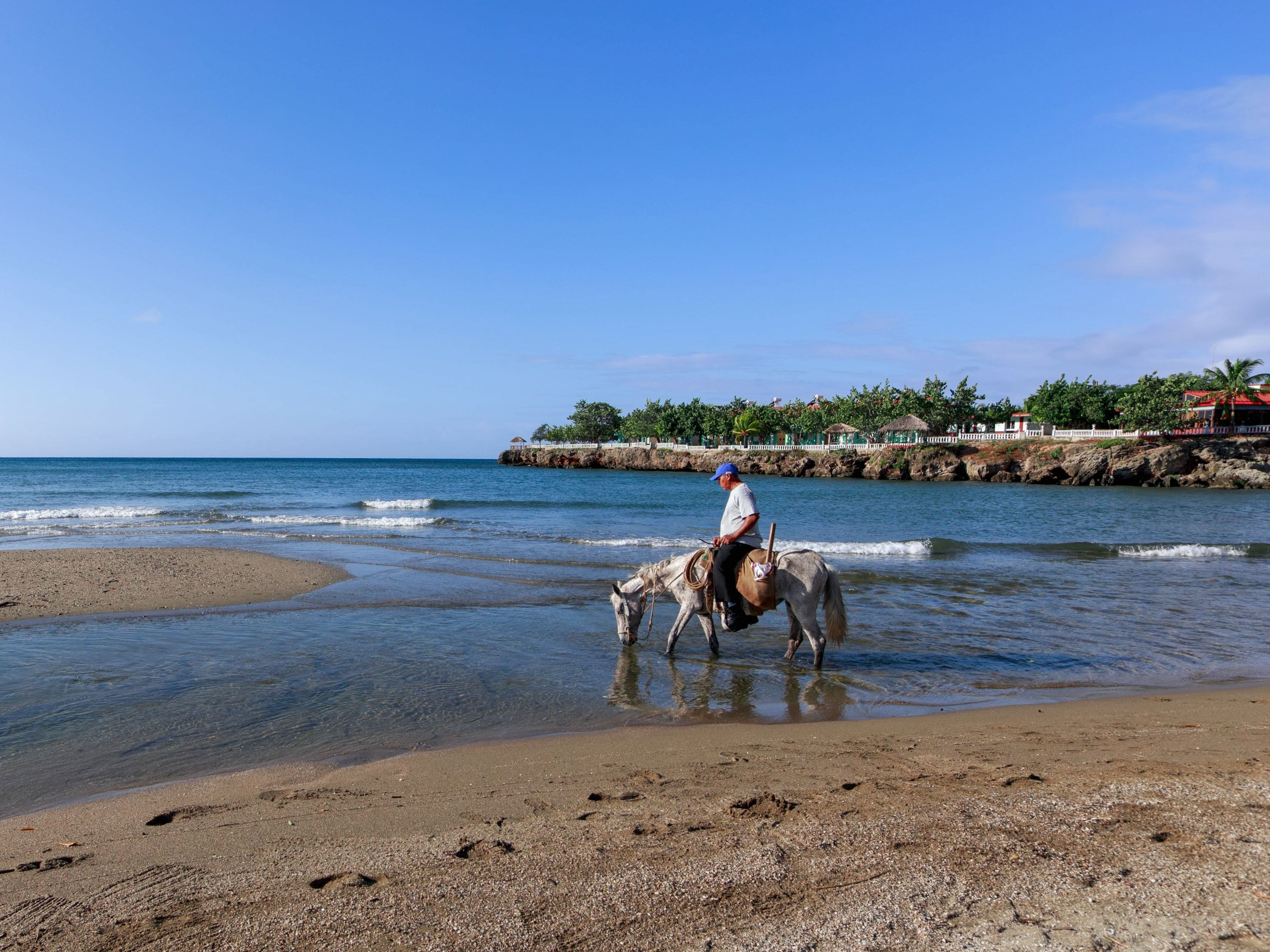 Rider on horseback along the shore with volcanic peaks behind, Ometepe Island, Nicaragua