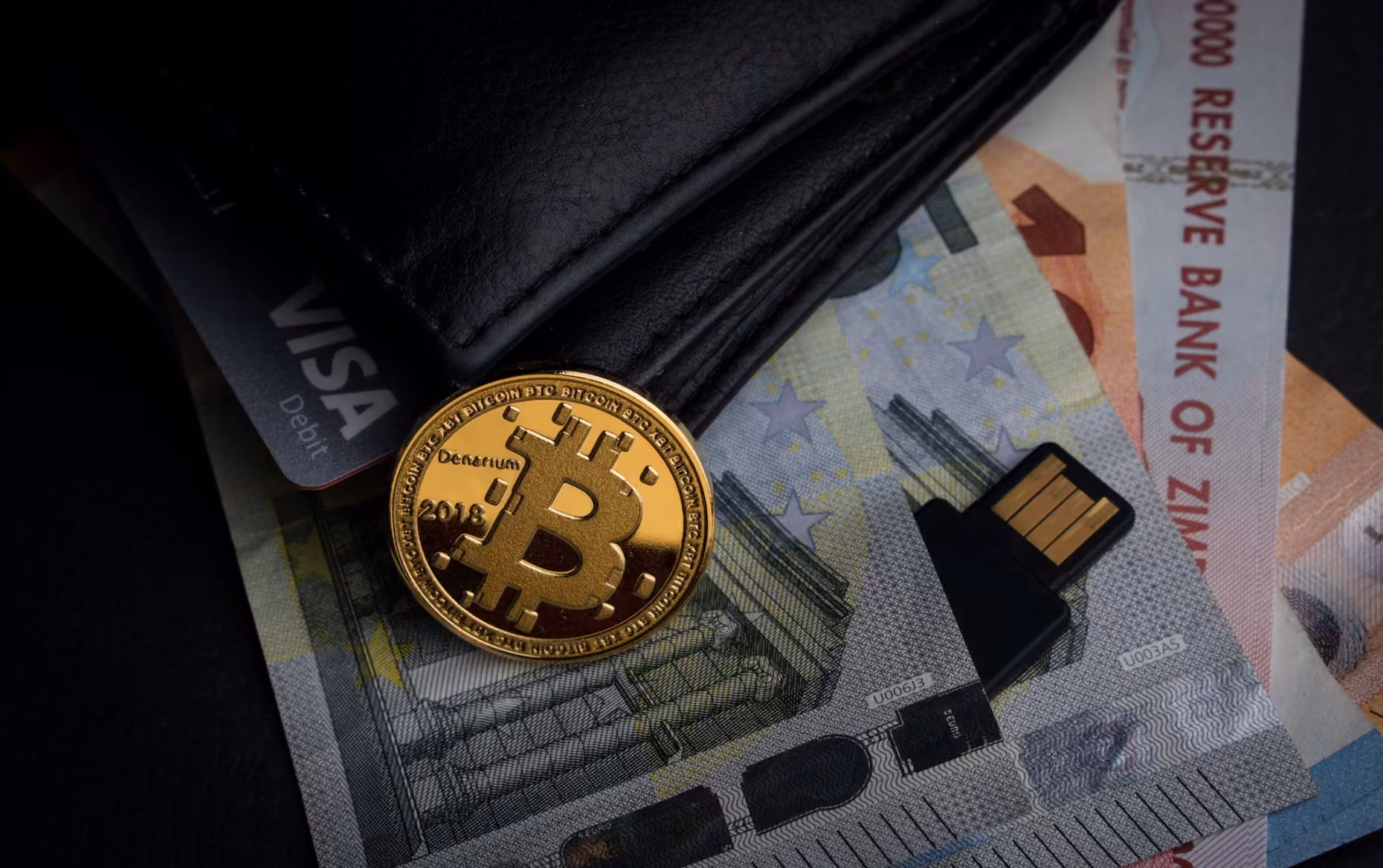  Bitcoin coin resting on a stack of cash