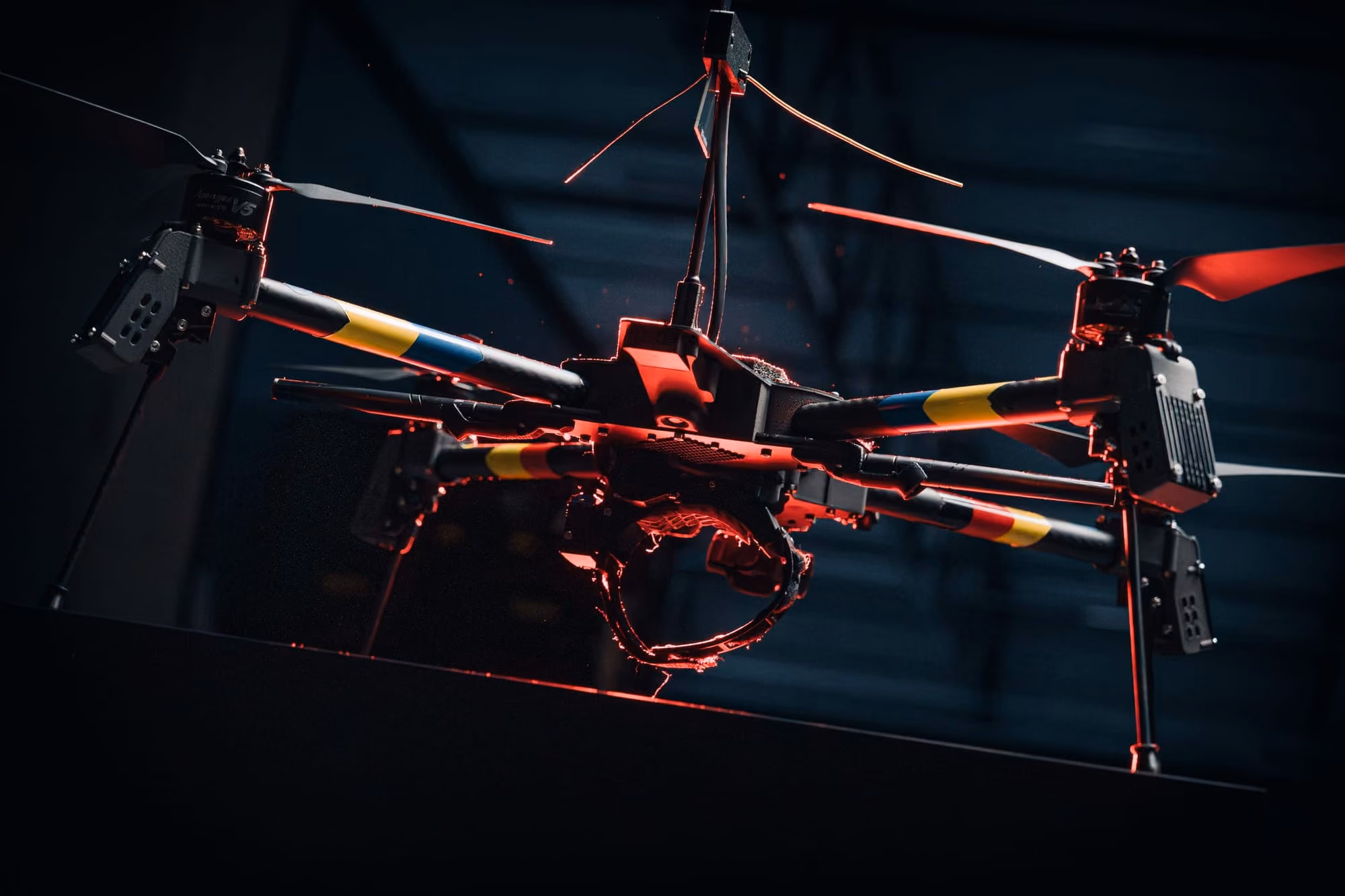 Quantum Frontline Industries drone with four propellers and red LED lighting in a dark indoor setting.