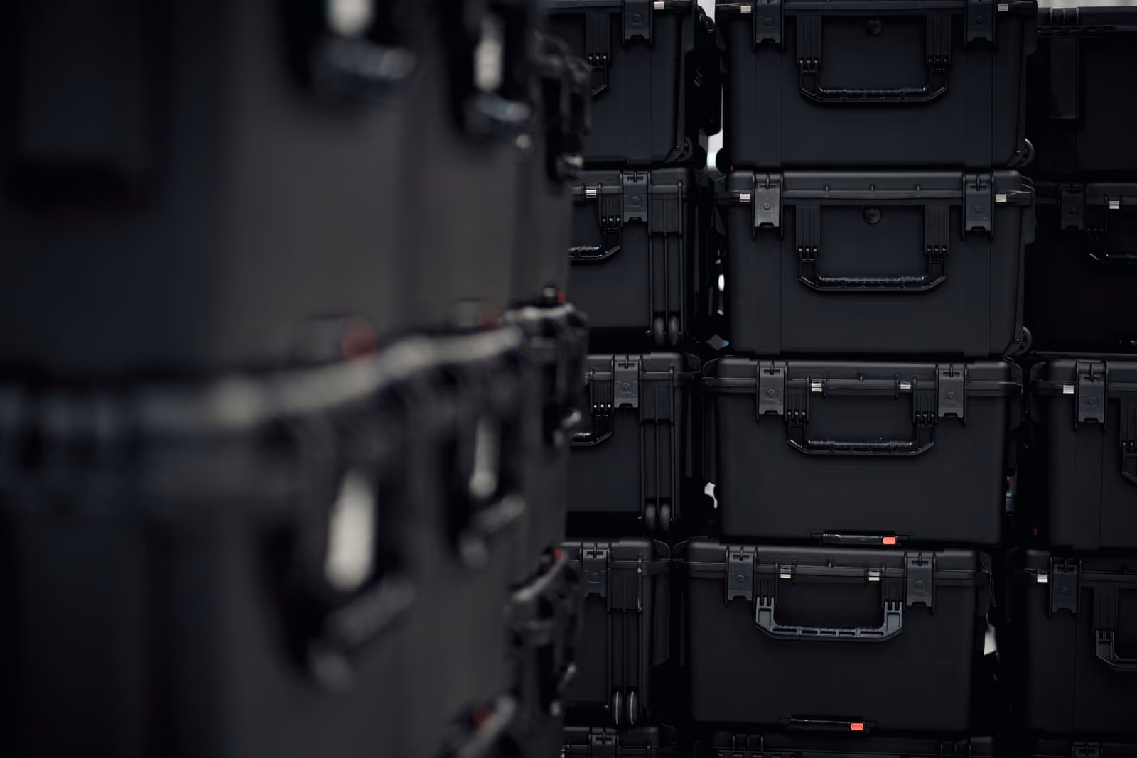 Stacked black rugged hard cases from Quantum Frontline Industries with handles and latches, arranged closely in rows.