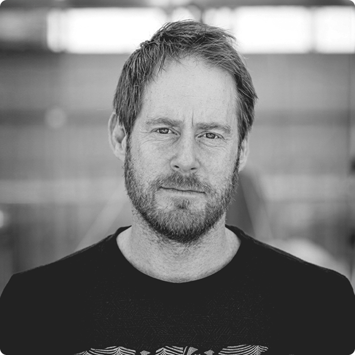 Black and white portrait of Nicolai with short hair and beard wearing a dark shirt.