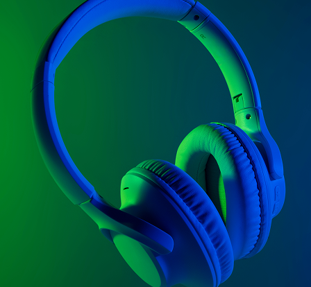 Over-ear wireless headphones illuminated with blue and green lighting.
