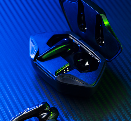 Wireless black earbuds with an open charging case on a textured surface under blue and green lighting.