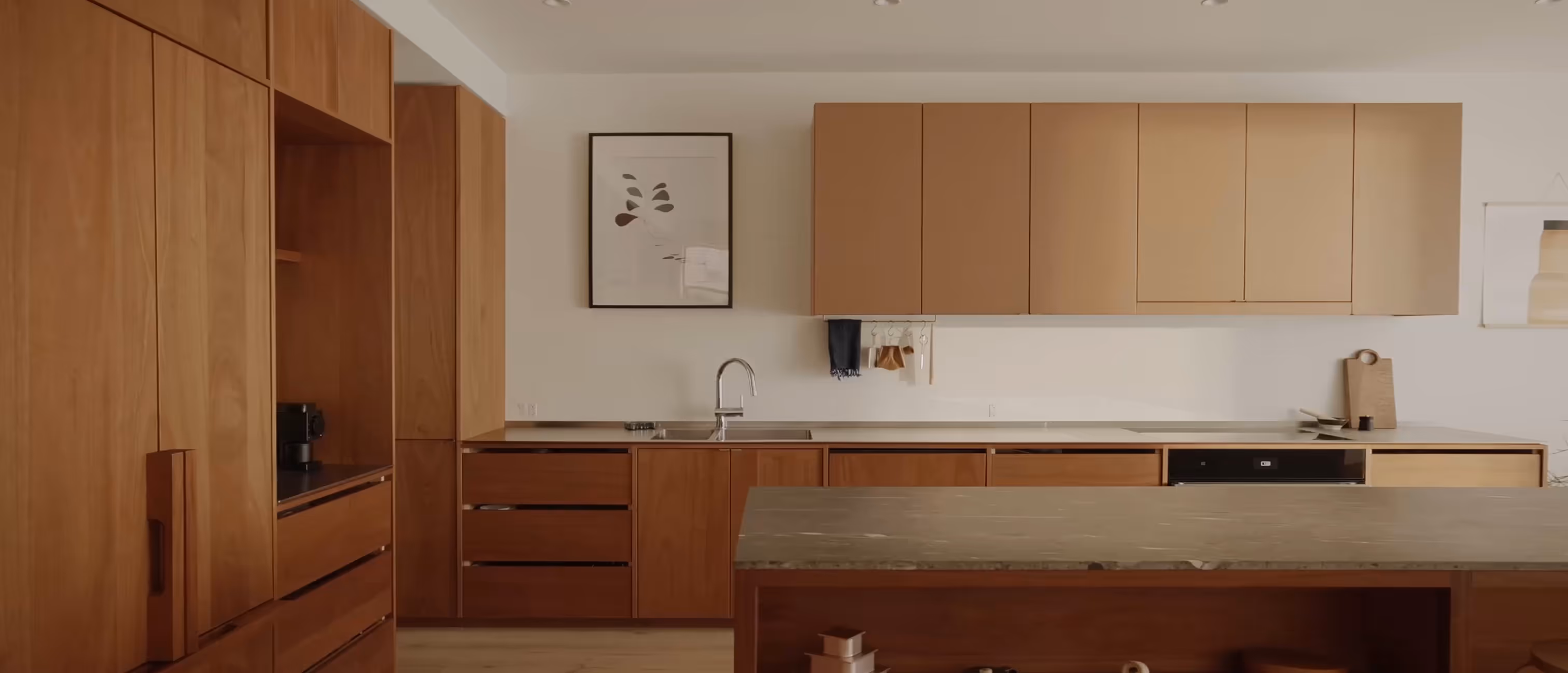 Modern kitchen with wooden cabinets, marble countertop island, and neutral wall decorations.
