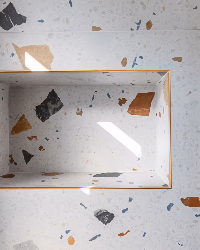 Terrazzo surface with colorful stone chips and a rectangular recessed niche in the center.