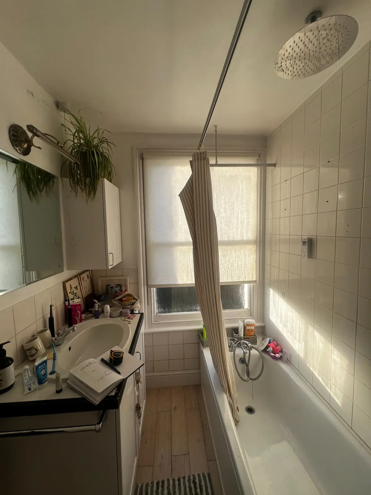 Bathroom before renovation, with a bath along one wall and the basin and storage opposite