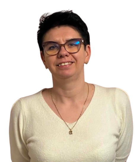 Smiling woman with short black hair and glasses wearing a white sweater and necklace.