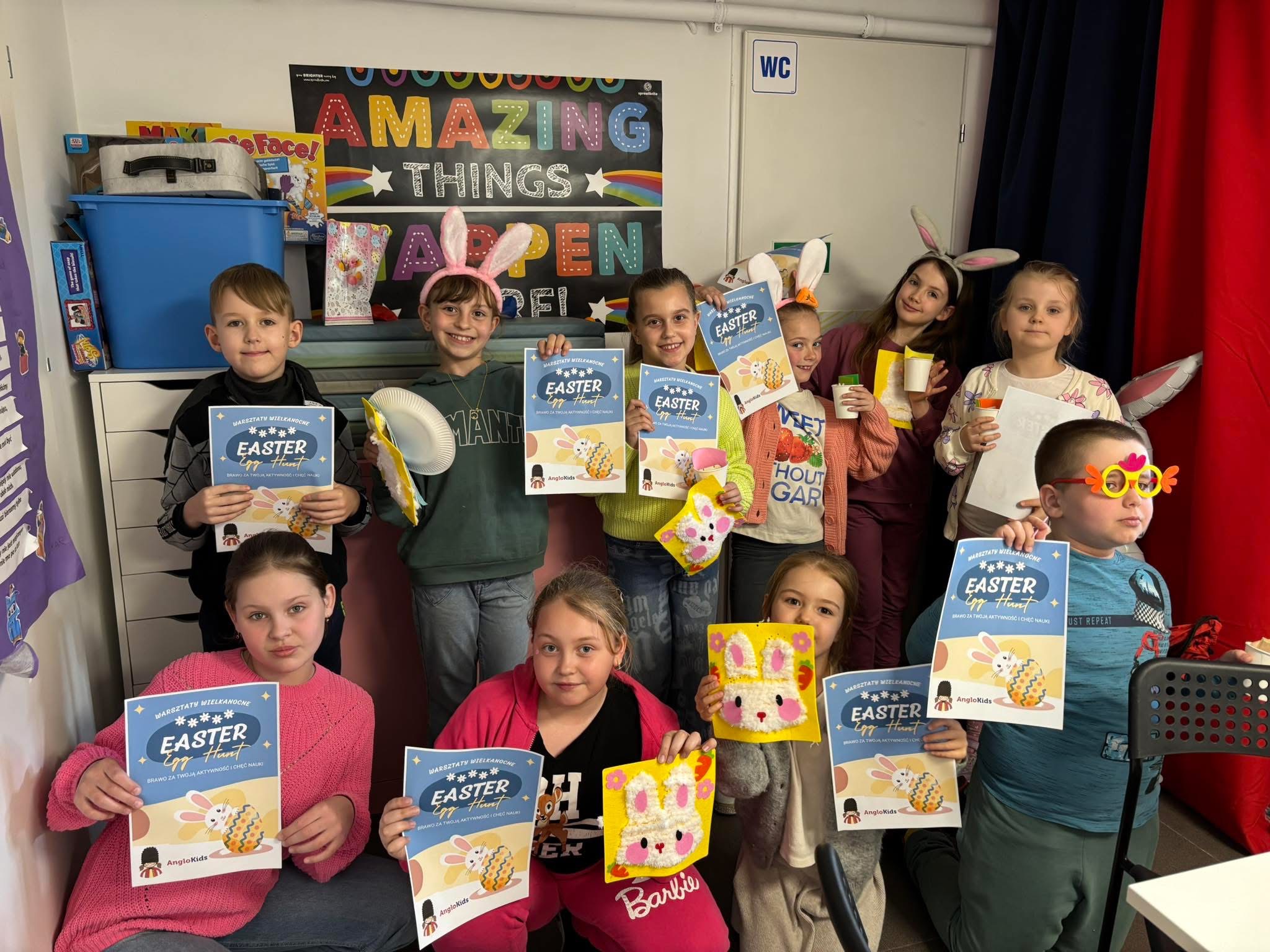 Group of children holding Easter certificates and crafts, some wearing bunny ears and festive glasses.
