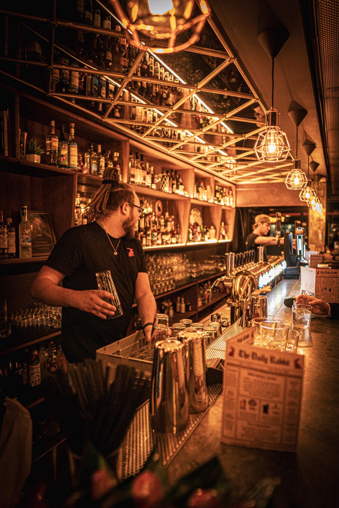 Bartender behind the bar at Red Rabbit Pub, Oslo, with a shelf of drinks in the background