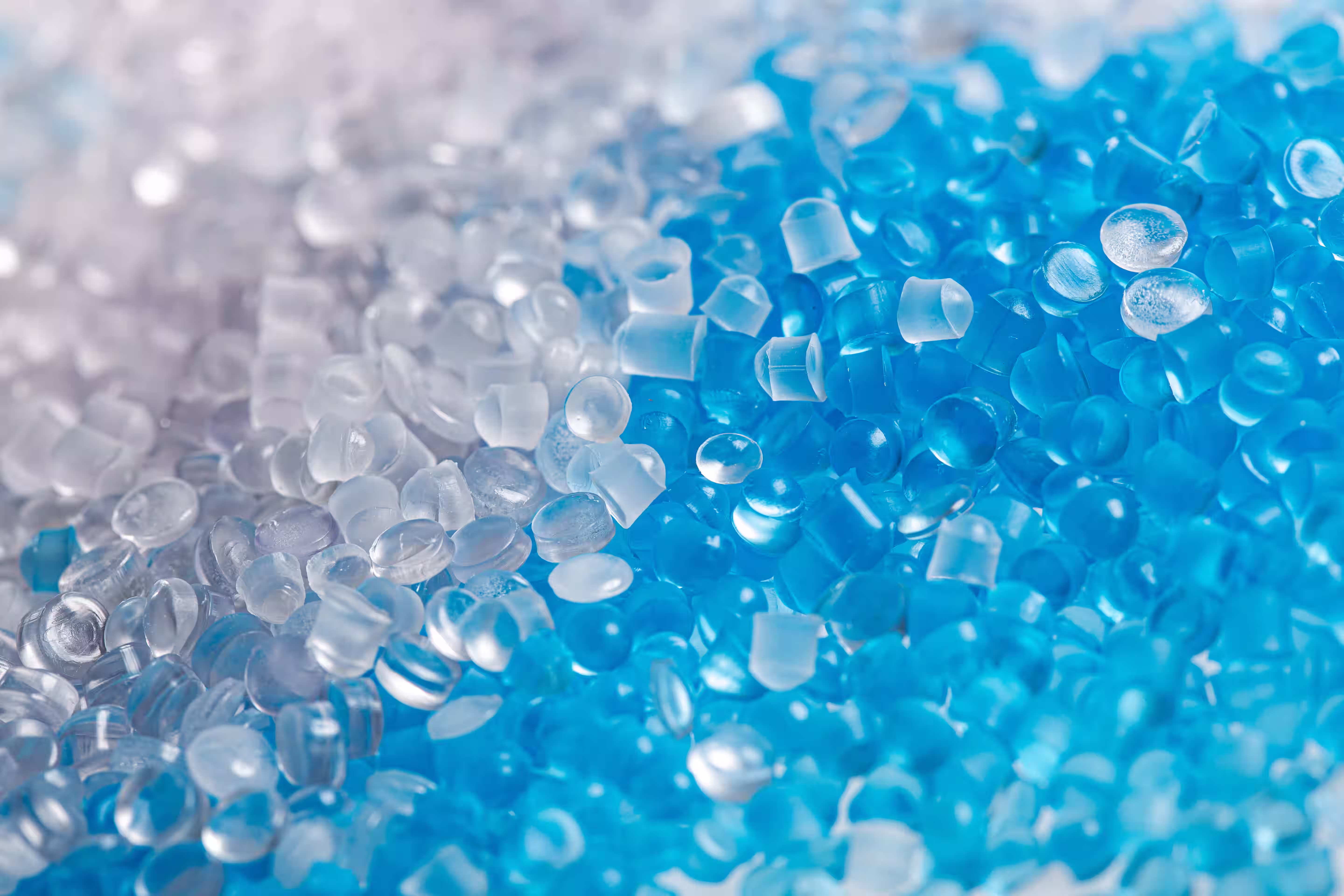 Close-up of translucent white and blue polymer plastic pellets.