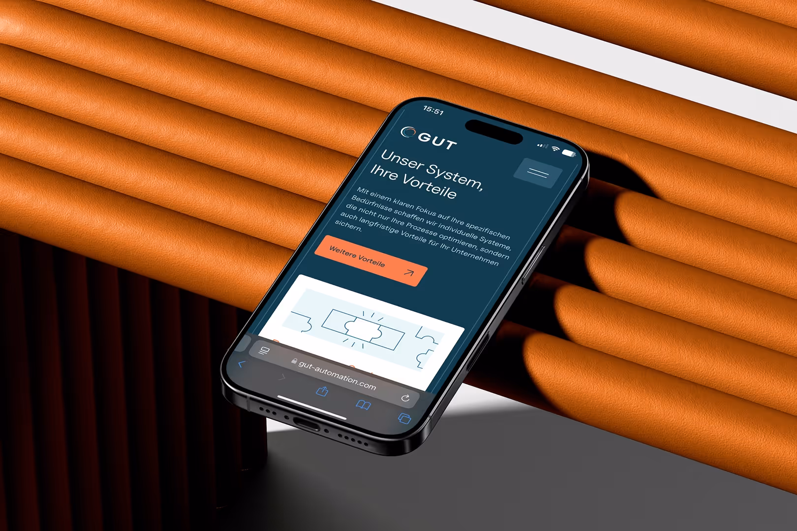 Smartphone zeigt die Webseite von GUT mit Text über Systemvorteile vor orangefarbenem, gerolltem Hintergrund.
