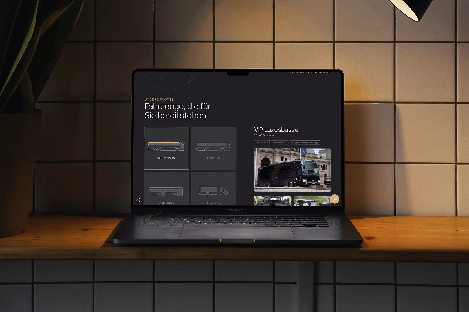 Laptop auf einem Holztisch zeigt eine Website mit Fahrzeugen zur Vermietung, speziell VIP Luxusbusse.