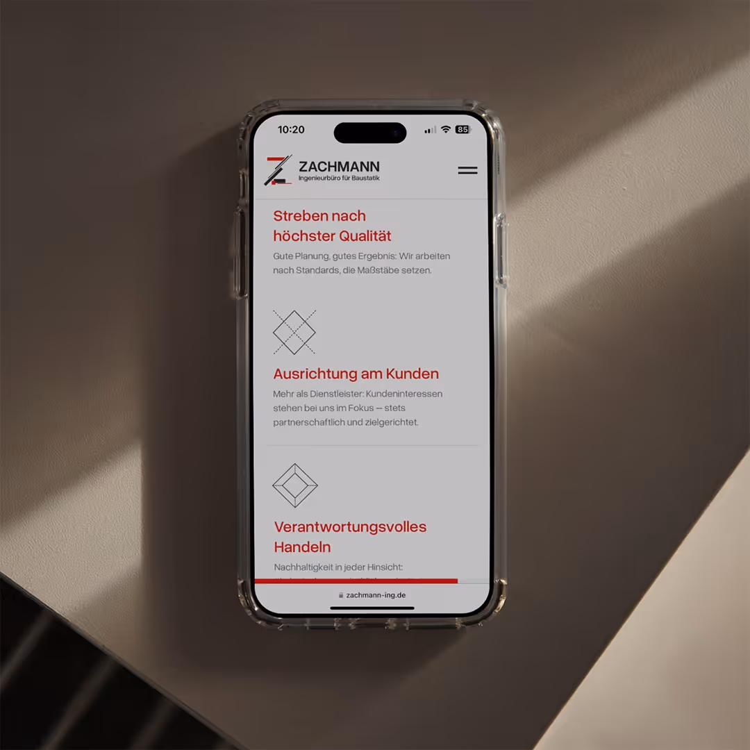 Smartphone zeigt Webseite von ZACHMANN Ingenieurbüro mit Abschnitten zu Qualitätsstreben, Kundenorientierung und verantwortungsvollem Handeln.