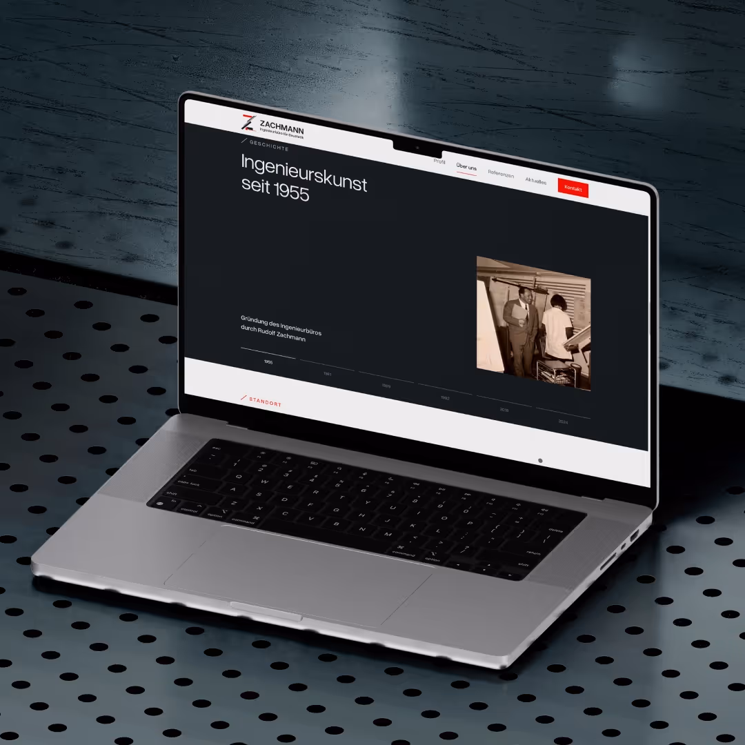 Offener Laptop zeigt Webseite mit Überschrift Ingenieurskunst seit 1955 und historischem Foto von Personen in Ingenieurbüro.