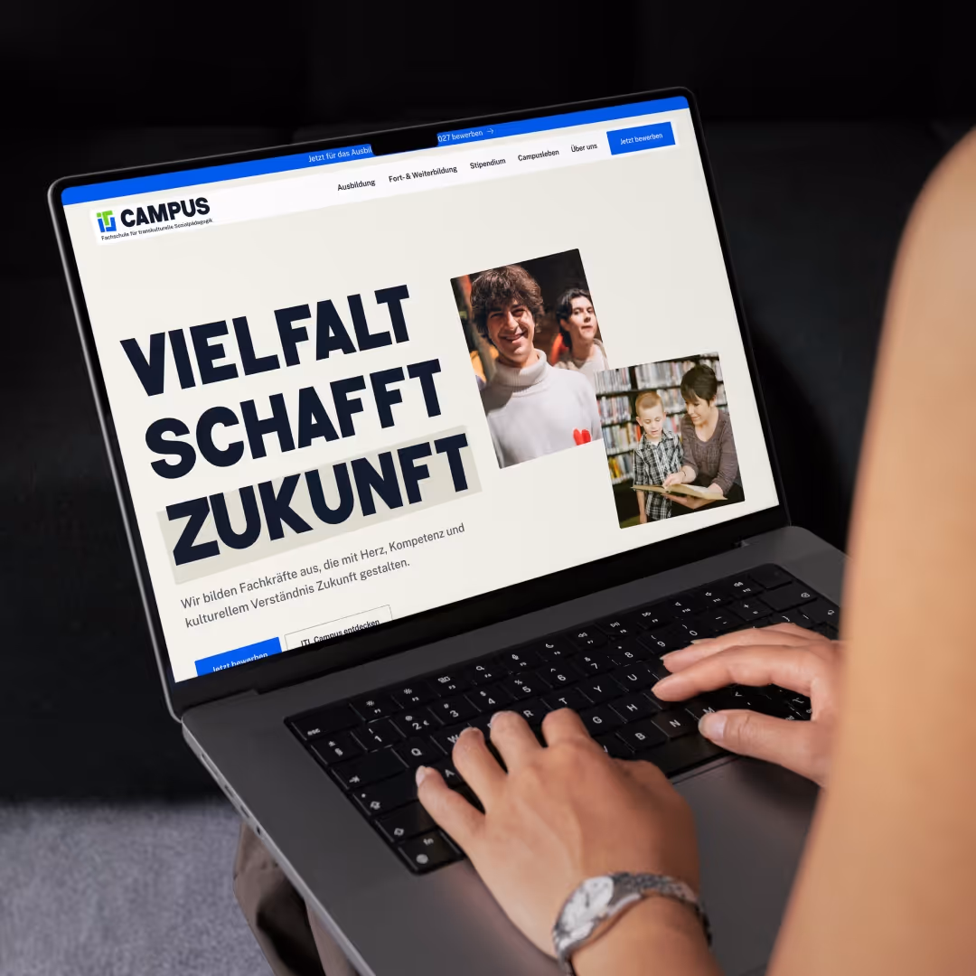 Laptopbildschirm zeigt die Website von IT CAMPUS mit dem Slogan 'Vielfalt schafft Zukunft' und Bildern von Menschen, dazu eine Person tippt auf der Tastatur.