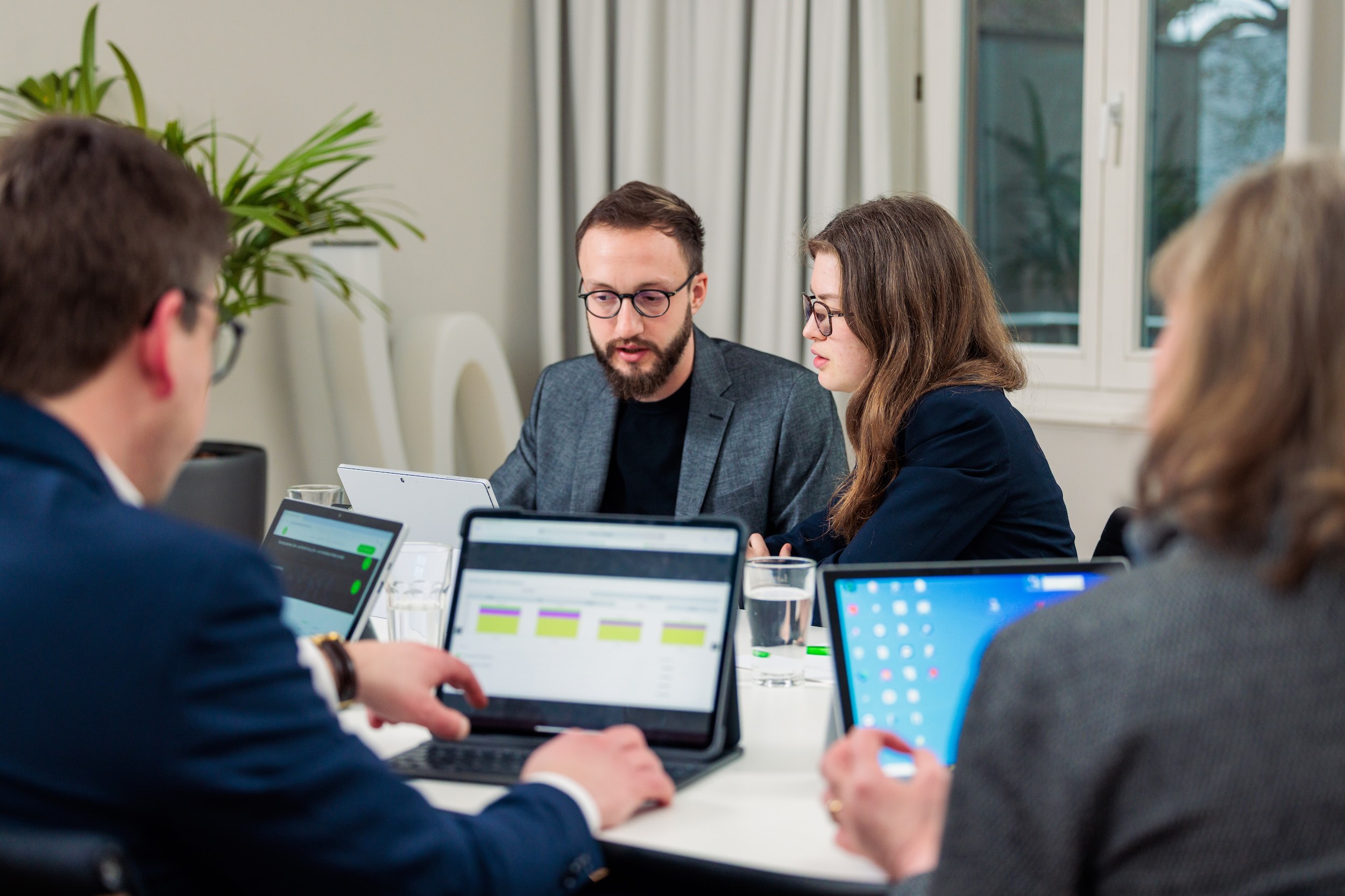 Mehrere Personen sind in einem Konferenzzimmer an einem Tisch und arbeiten an Laptops.