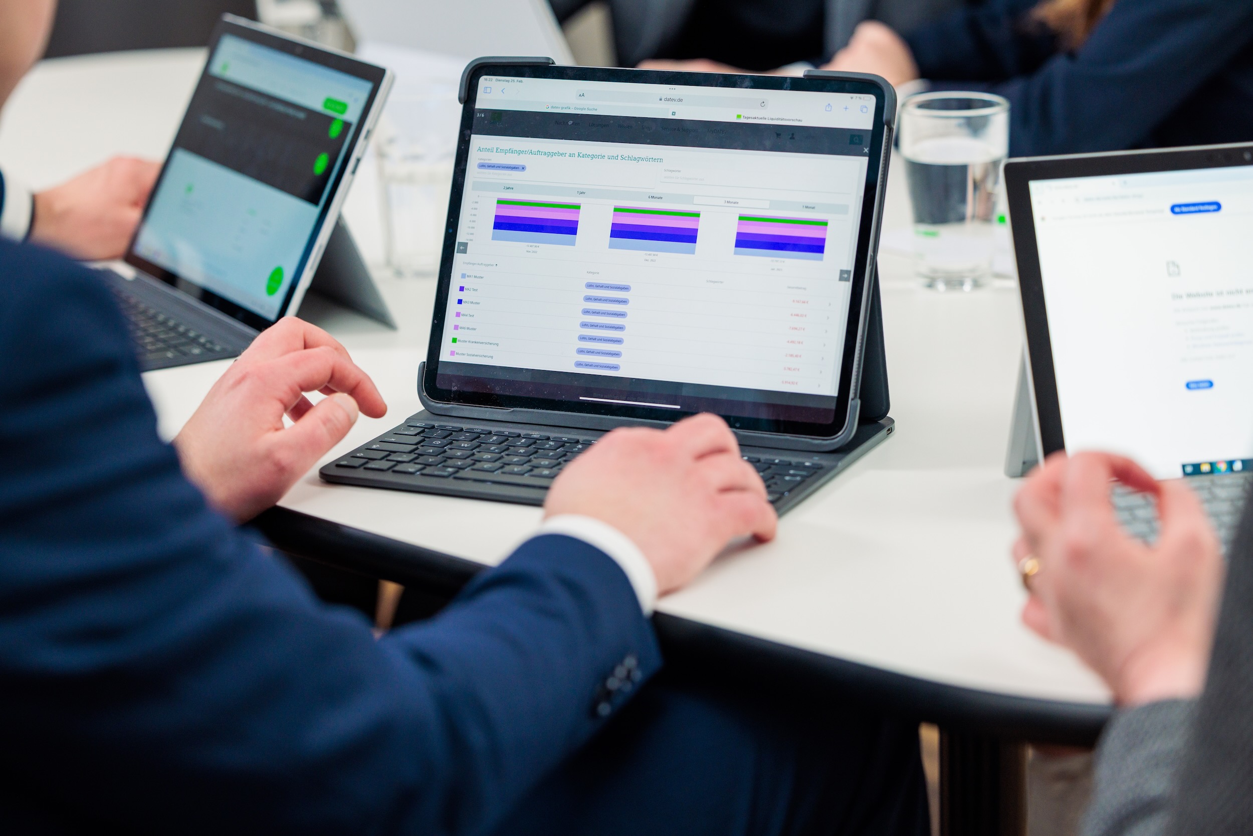 Nahaufnahme von mehreren Laptops. Man sieht Hände von Personen in Businesskleidung.