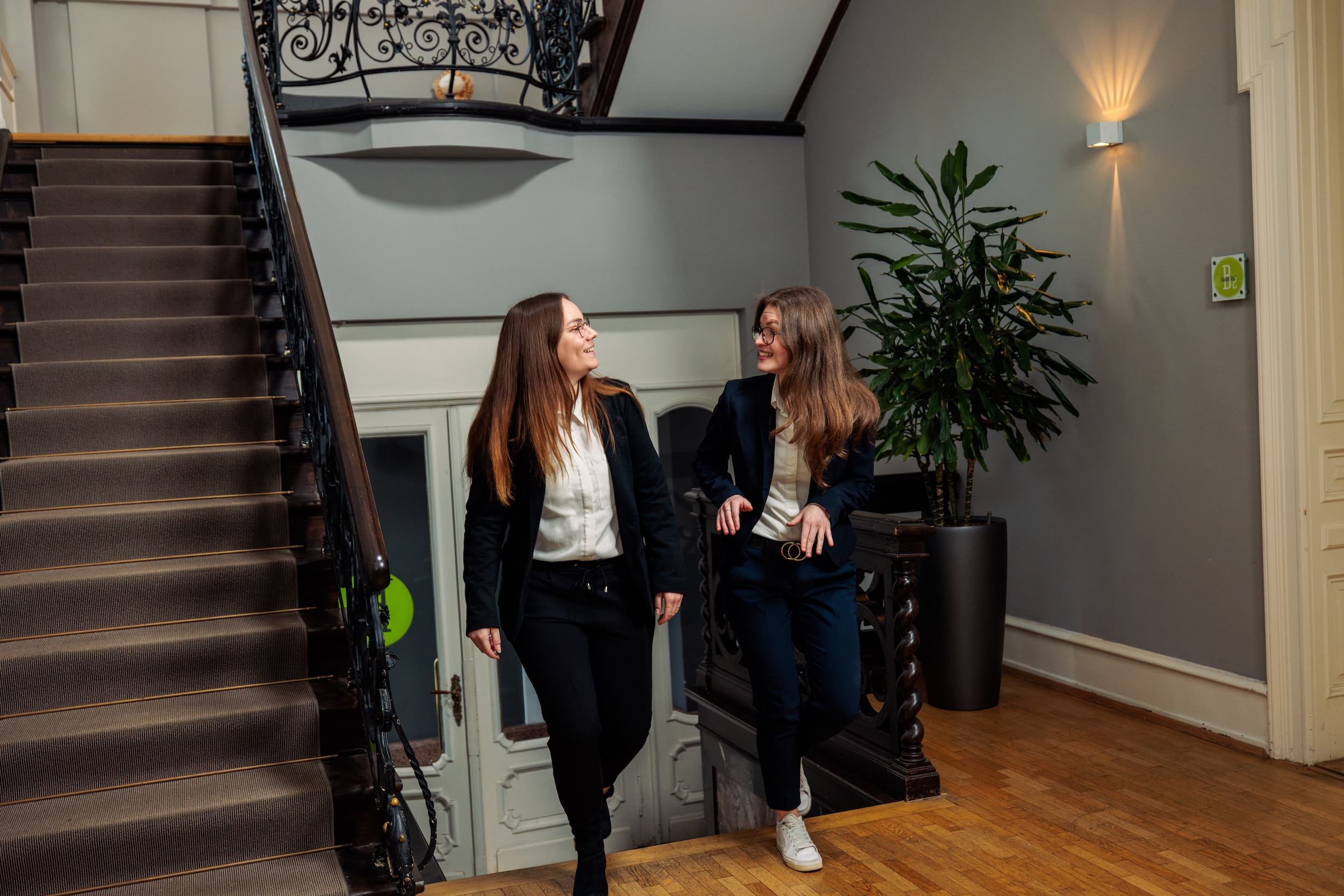 Zwei Frauen laufen eine Treppe hoch und unterhalten sich fröhlich dabei.