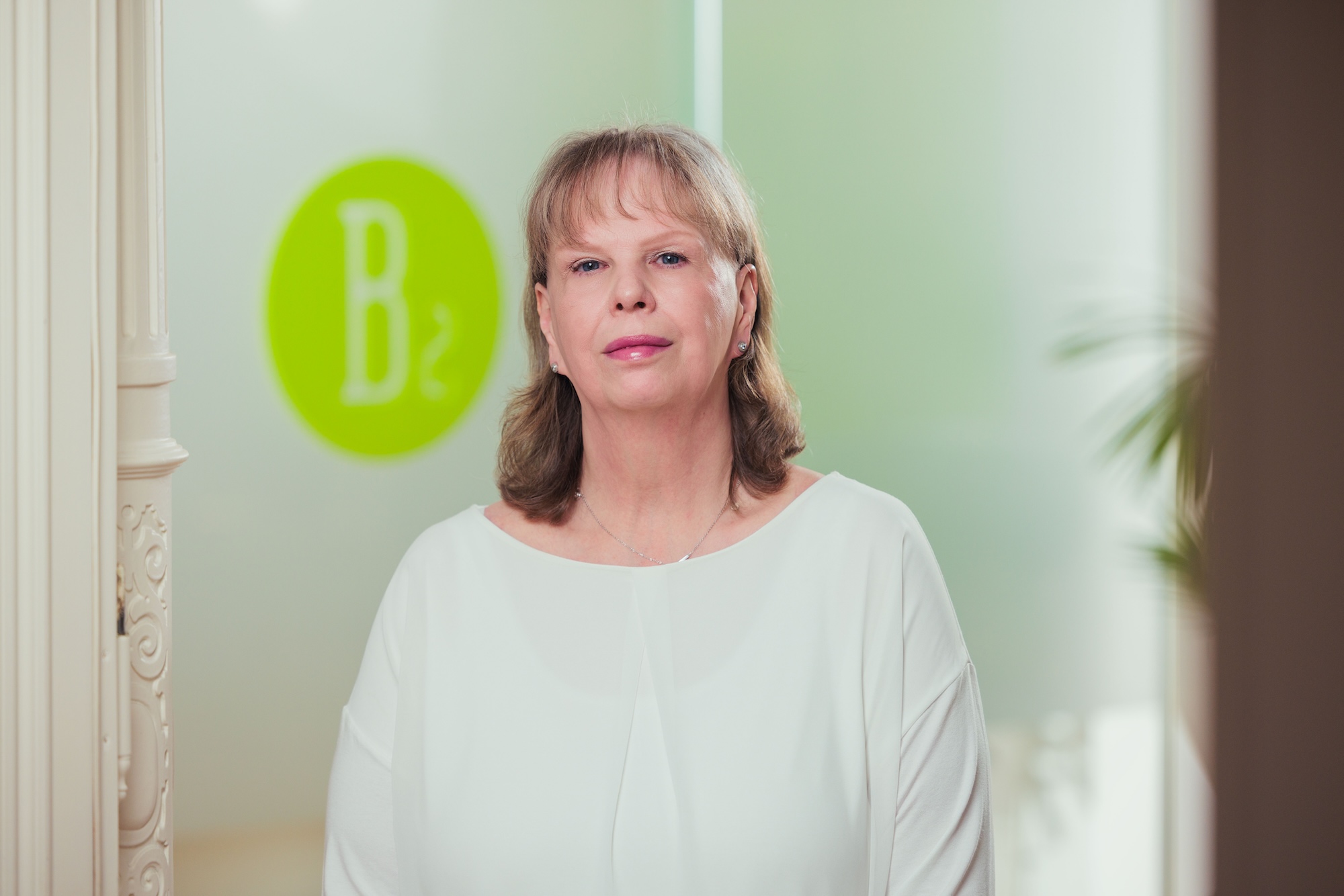 Porträt einer blonden Frau mit weißem Oberteil.