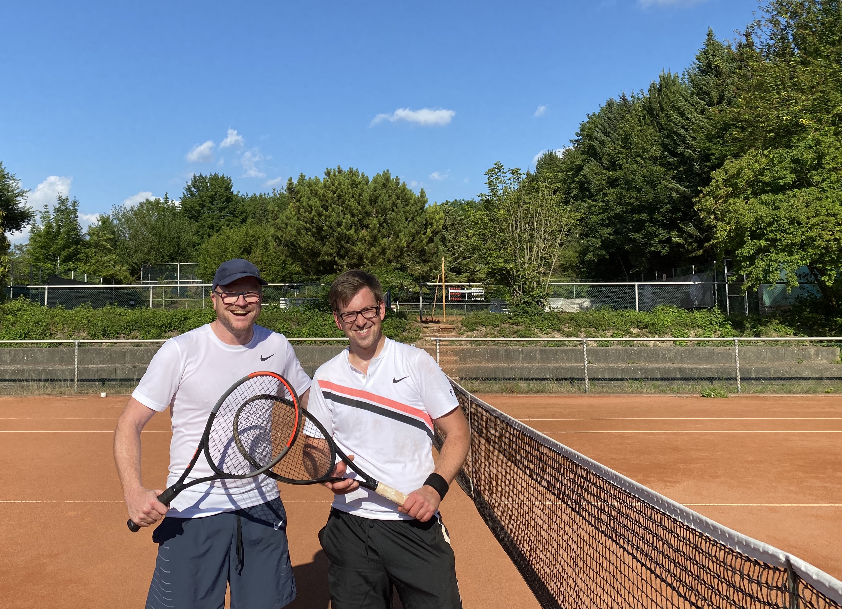 Zwei Männer sind auf einem Tennisplatz und halten Tennisschläger in der Hand.