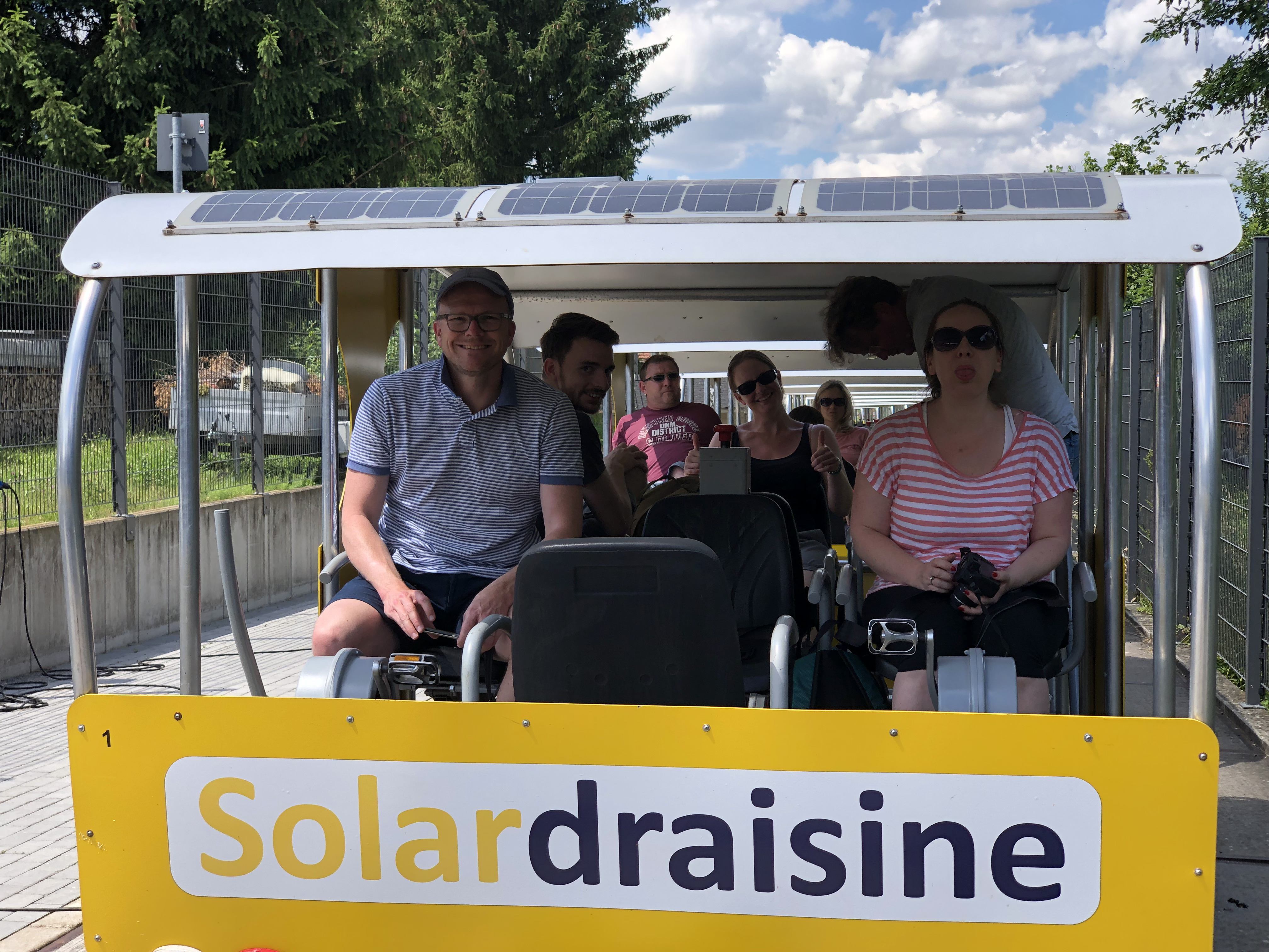 Mehrere Mitarbeiter sitzen in einer Draisine, die mit Solarstrom betrieben wird.