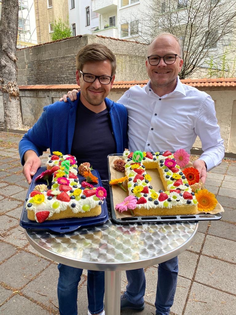 Zwei Berater der Kanzlei halten eine Torte in Form einer 10.