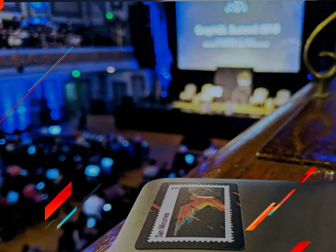 A laptop with a postage-stamp sticker in the foreground of a large, blue-lit conference hall