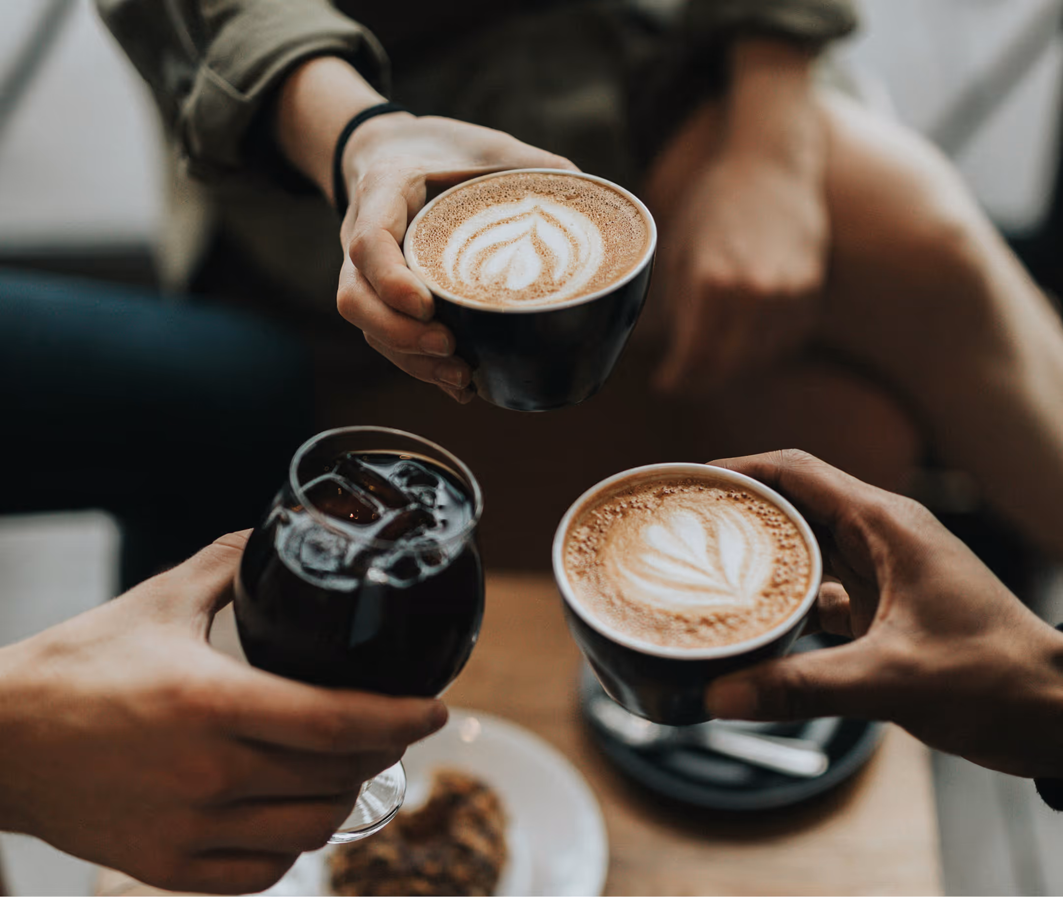 A group of friends cheers their coffee beverages.