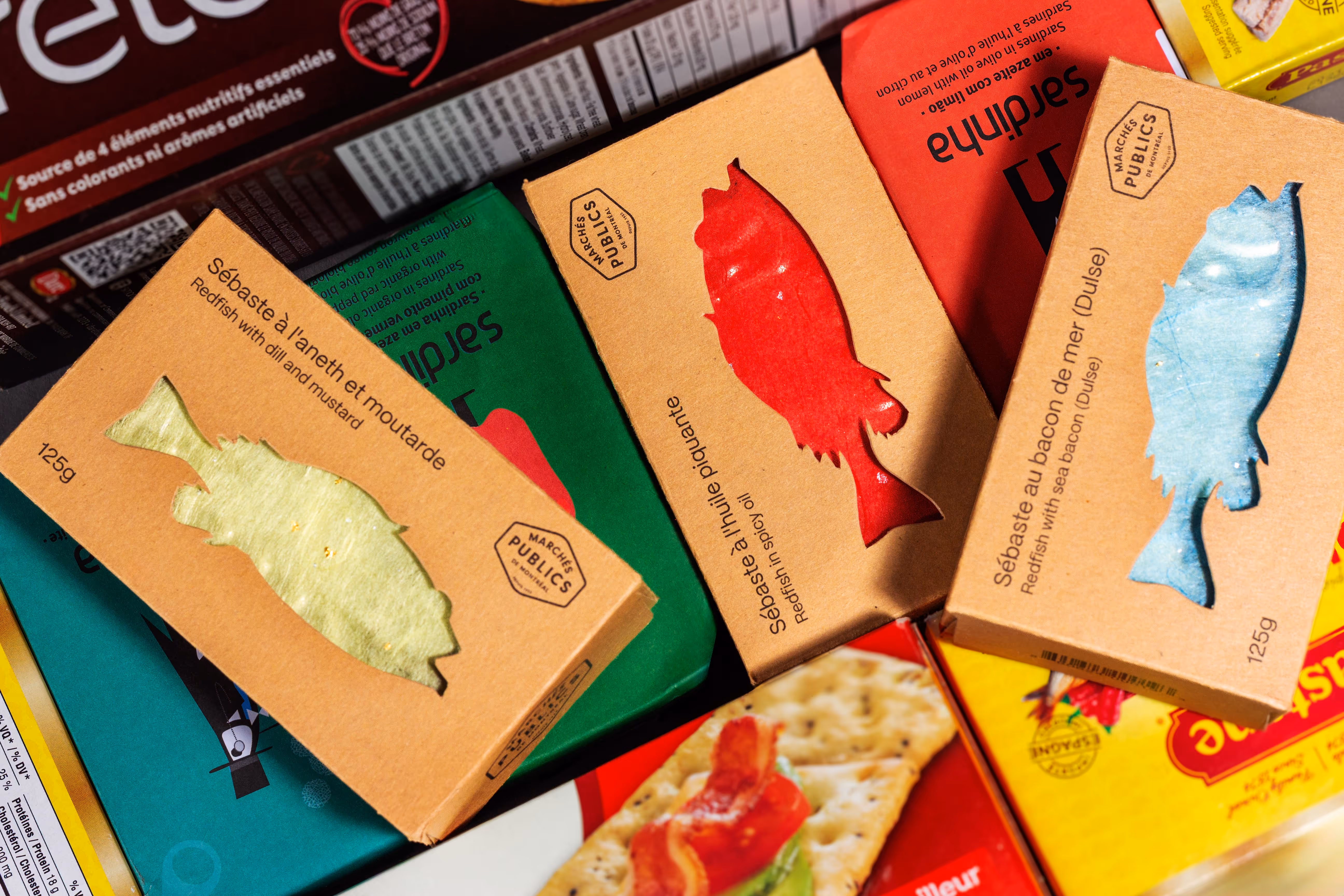 The tinned fish product is placed in context, with other packages of tinned fish and crackers. Photo taken by © Kayleigh Lord.