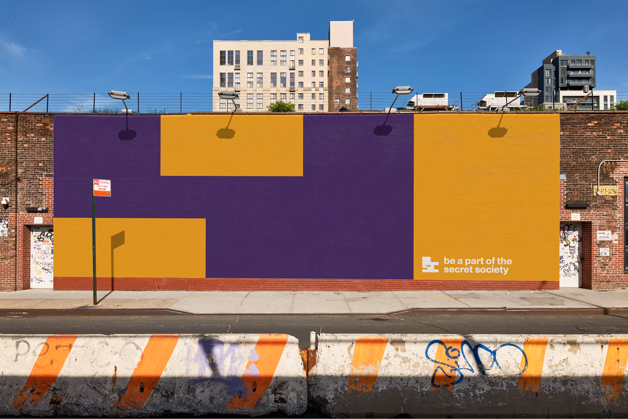 A mockup of the deconstructed logo in orange and purple on a brick wall, with day time lighting. 