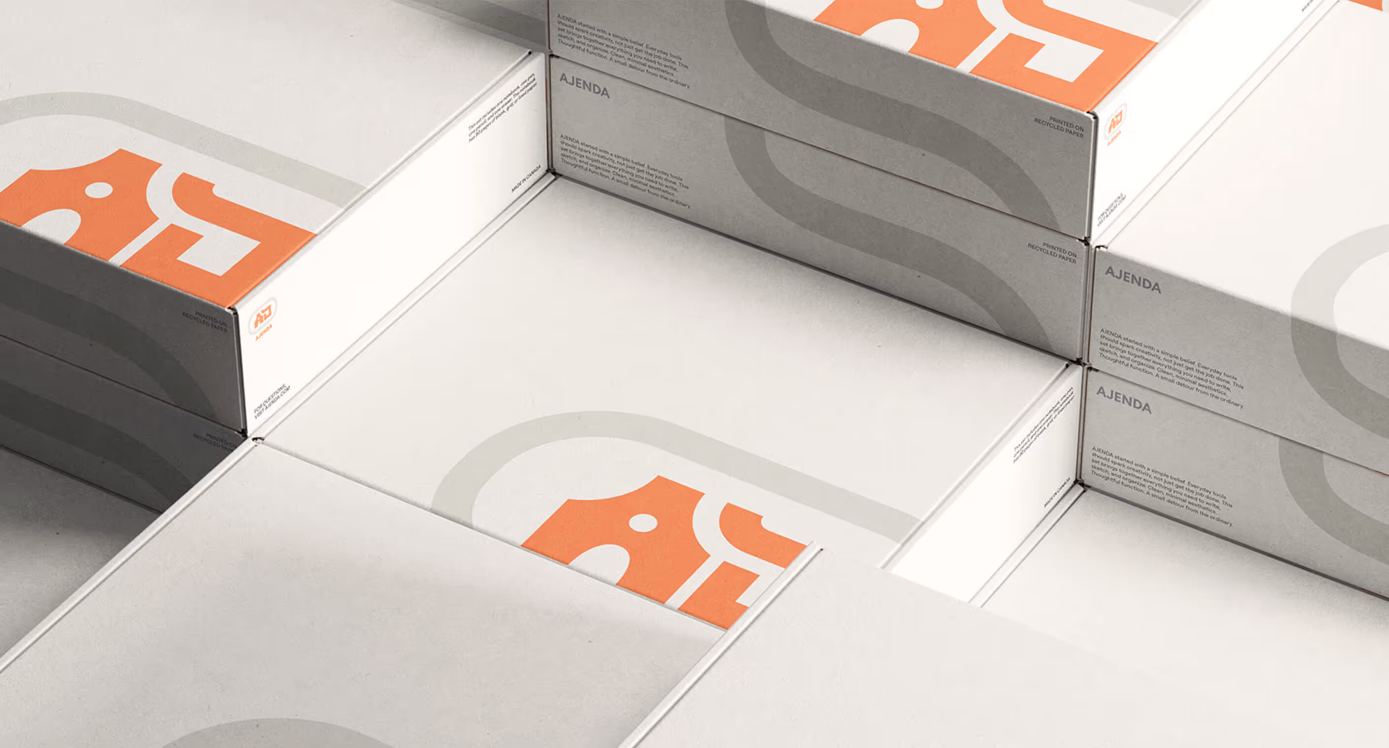 Ajenda box design with orange and beige logo mark placed on recycled material