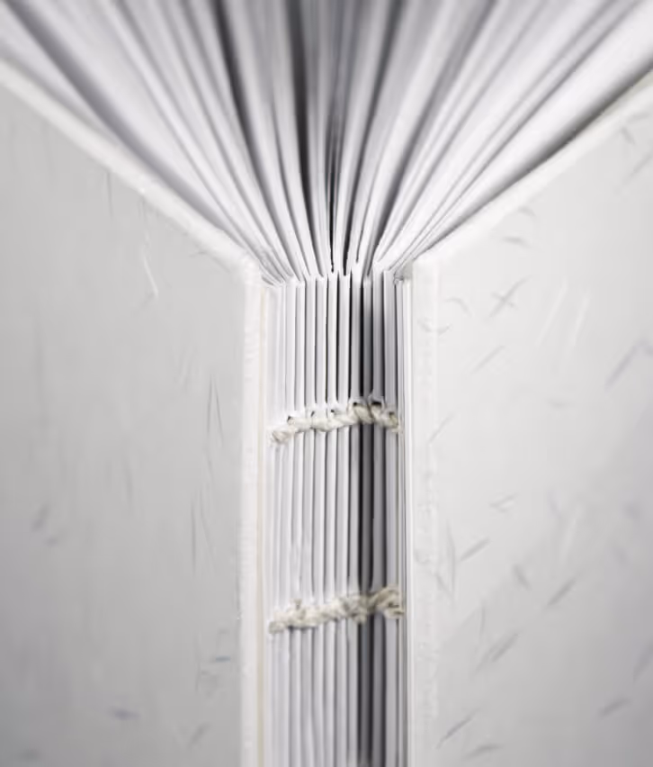 Close-up of coptic stitch binding with exposed spine and linen thread on handmade cookbook