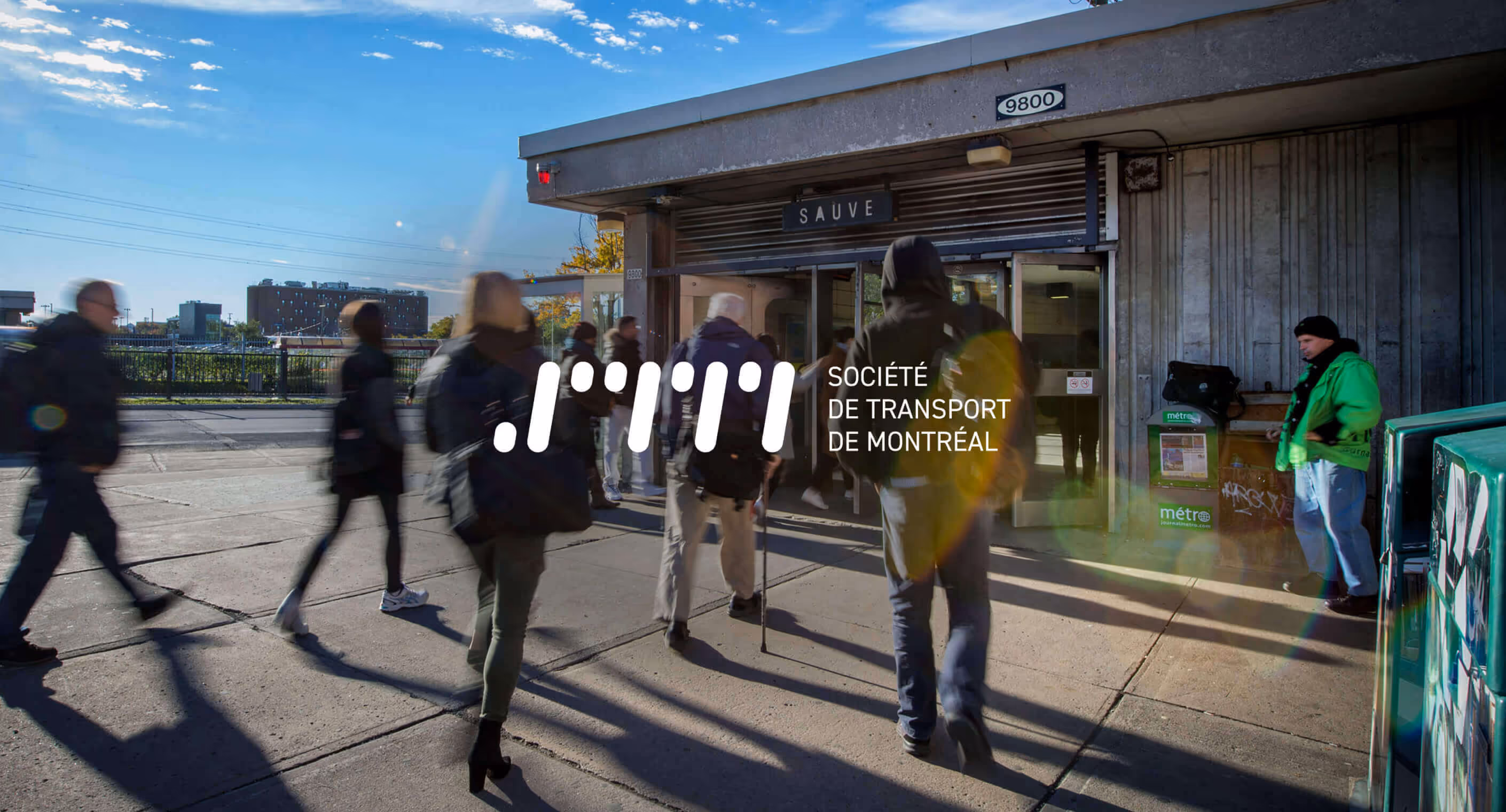 Redesigned STM logo in white placed on image of people entering metro entrance