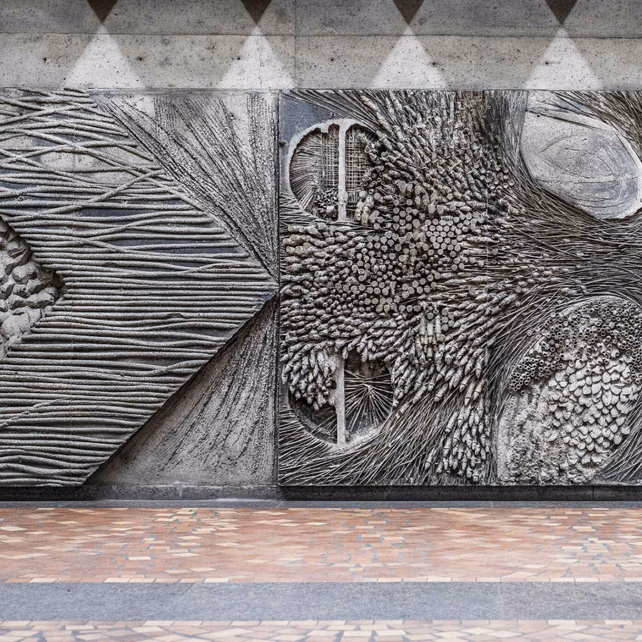 Carved stone artwork on metro wall with abstract geometric patterns