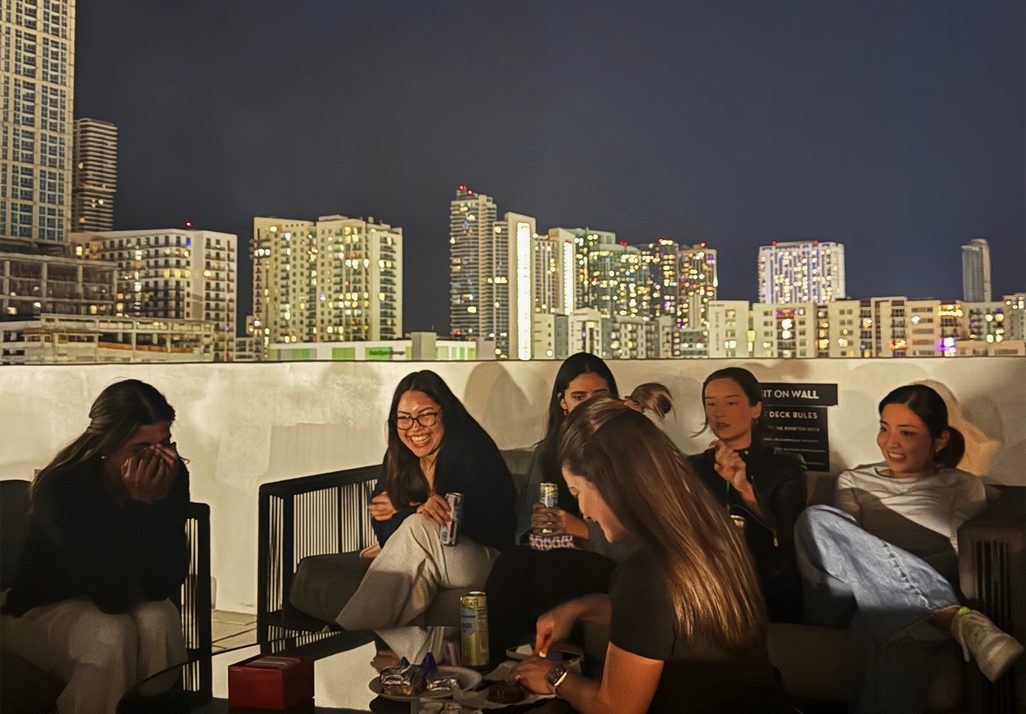 A Women's Crew on a rooftop with the Miami skyline behind them
