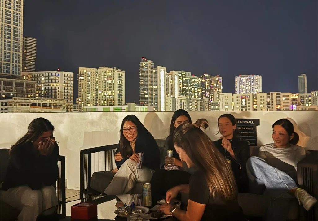 A Women's Crew on a rooftop with the Miami skyline behind them