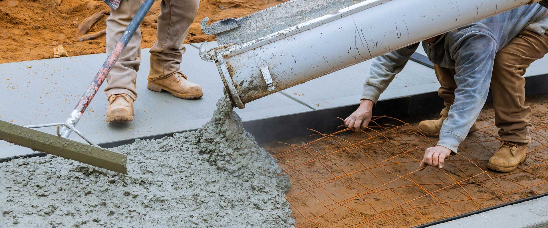 Concrete crew pouring and finishing a fresh concrete surface during installation