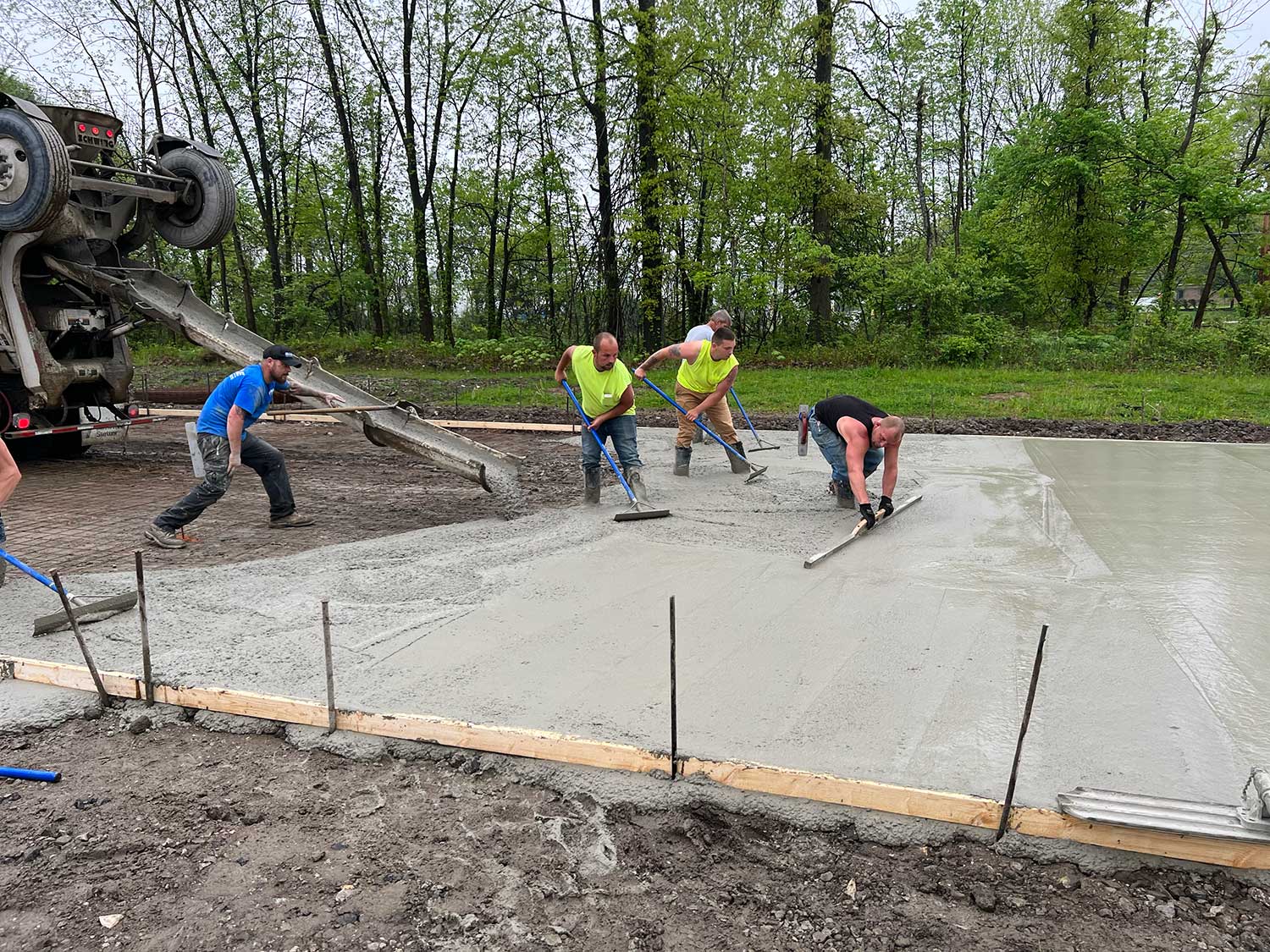 Concrete placement and finishing process showing crew leveling and smoothing the surface